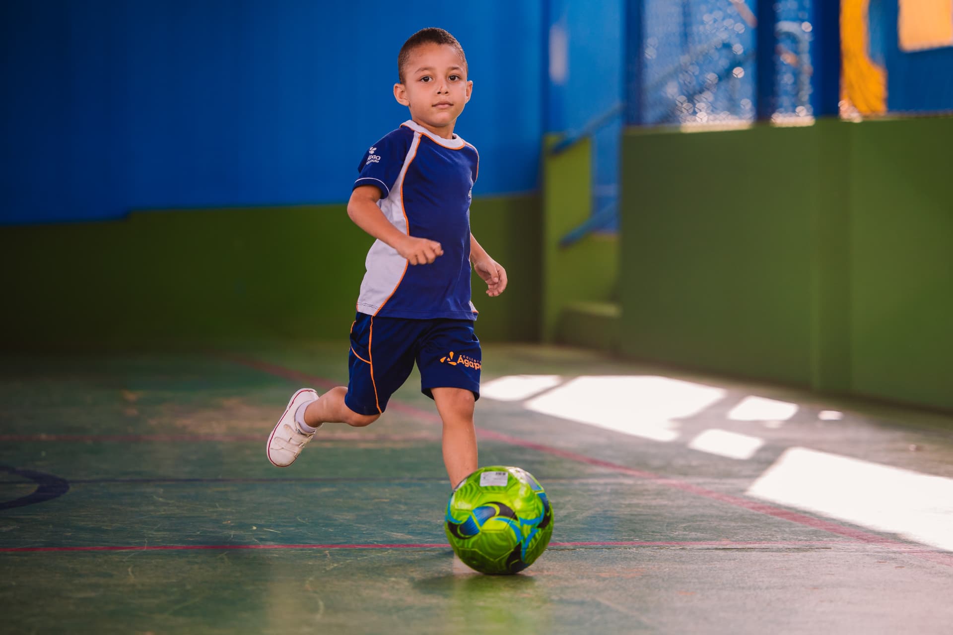 Criança jogando futsal na quadra
